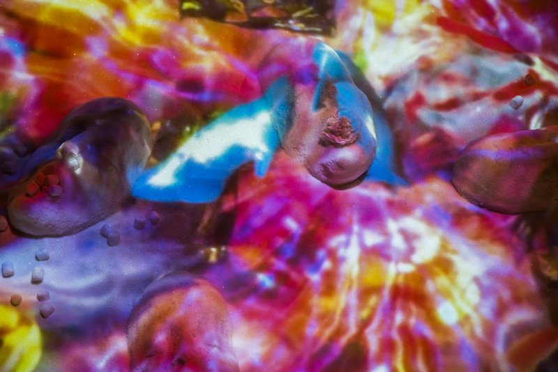 Abstract digital art with glowing blue and white forms on a textured surface, surrounded by vibrant reds, oranges, and purple