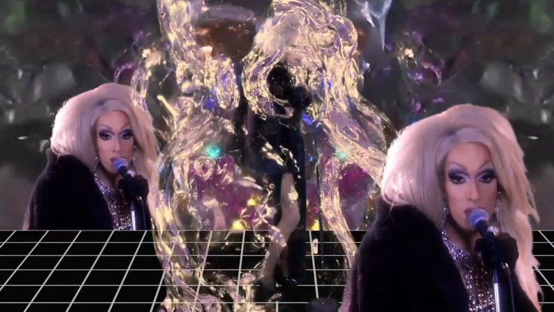 Two drag queens with blonde wigs and dark coats sing into microphones, mirrored over a grid and abstract liquid forms.