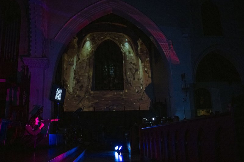 Scott N Andrew's "Vox Humana" (2024) shows a dark church interior with a large, arched projection of a stone archway.
