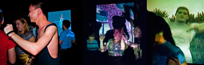 Multi-panel video installation showing people in a dark room, illuminated by video projections. Projections include figures, animals, and abstract shapes in blue, purple, and green hues.